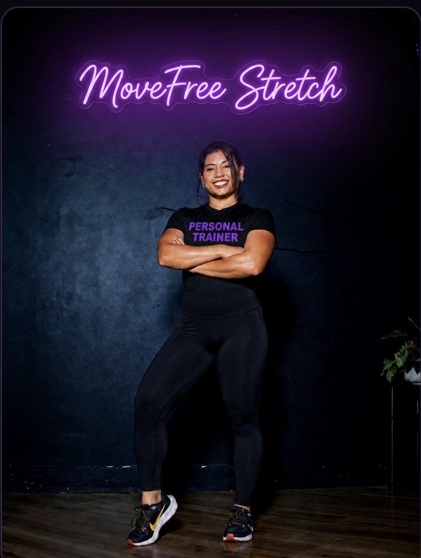 Personal trainer standing in front of the purple MoveFree Stretch neon sign